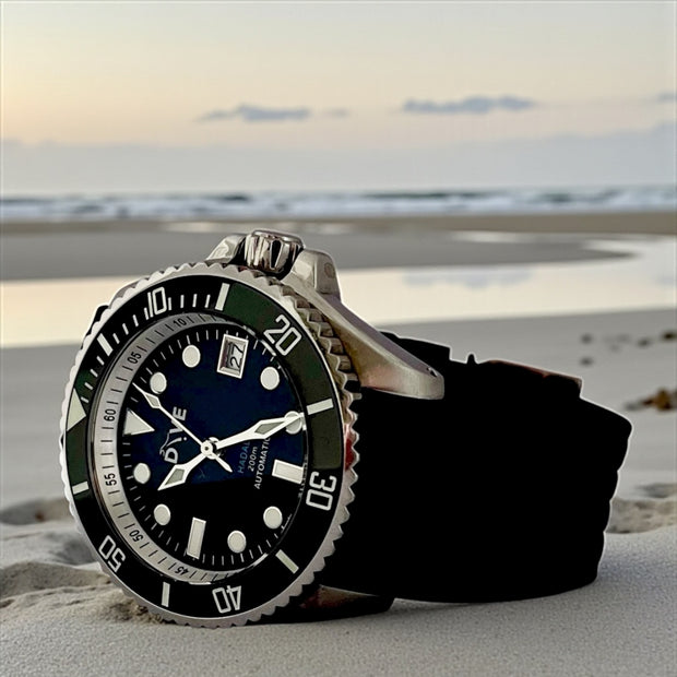 HAND-BUILT DIVERS WATCH HADAL showcasing a stainless steel case on a beach at sunset.