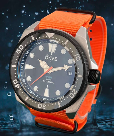 Hand-built divers watch HADAL TITAN Bead blasted finish, with black knurled bezel and crown, with black dial and bright orange NATO strap, water splash background